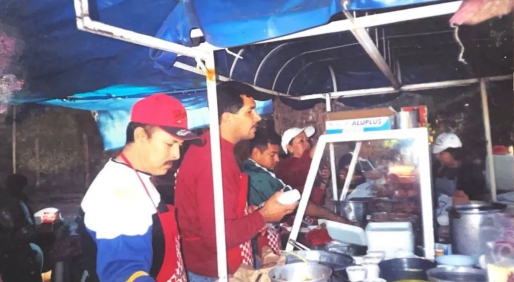 El equipo con mandiles rojos atendiendo bajo el toldo azul