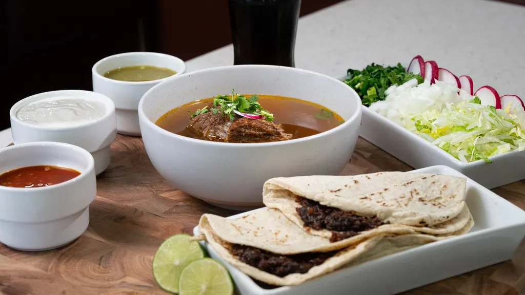 Orden de birria con salsas, crema y tacos de asiento