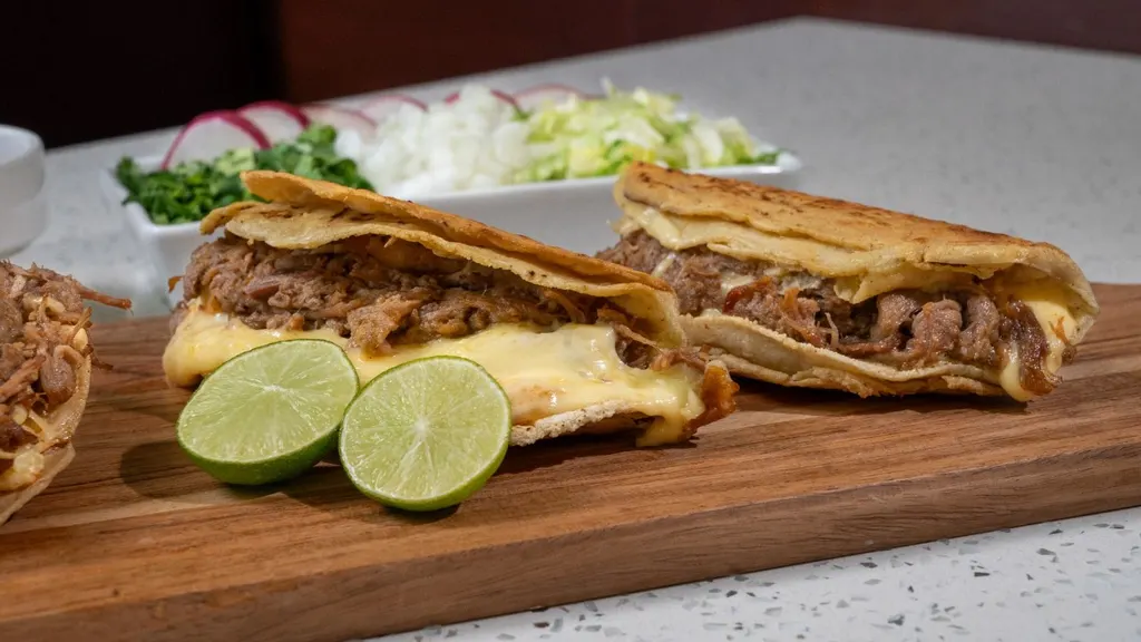 Dos tacos especiales de birria con queso, vistos de lado